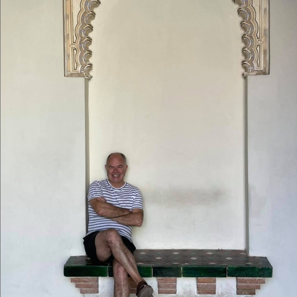Andy sitting down under an Arabic-looking arch. 